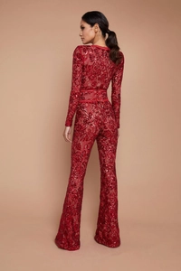 Detail of red sequin lace jumpsuit featuring a cinched waist belt and flared leg fit