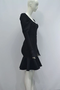 Détail de la robe bandage noire à col carré avec manches bouffantes et ourlet à volants
