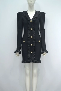 Detail of black mini bandage dress featuring deep V-neck, ruffle trim, and gold pearl buttons