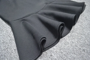 Détail d'une robe bandage noire avec des volants plissés et un tissu texturé de qualité