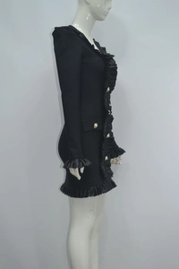 Detail view of black V-neck mini dress showing layered ruffles and golden pearl buttons
