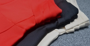 Detail of red, black and cream bandage fabric with dense knit texture and layered stitching