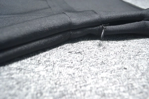 Gros plan sur la fermeture éclair invisible d'une robe bandage noire à texture tricotée