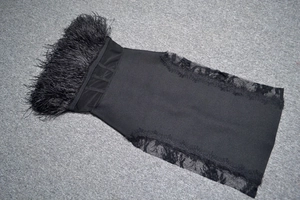 Detail of black bandage dress featuring ostrich feather trim and sheer lace side panels