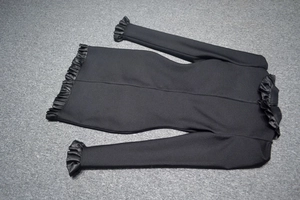 Close-up of black bodycon dress with satin ruffle trim on the sleeves and hemline