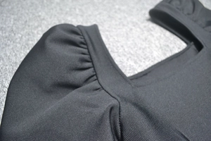 Détail de l'encolure carrée et des manches bouffantes sur une robe bandage noire
