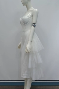 Detail of white tube bandage dress featuring layered mesh ruffles and a slim fit waist