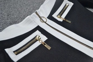 Détail de robe bandage avec fermetures éclair dorées et bordures blanches contrastées