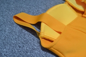 Detailed close-up of yellow bandage dress showing elastic straps and reinforced stitching