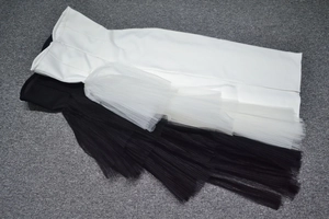 Detail of black and white strapless mesh dresses showing layered tulle ruffles and texture