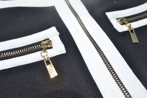 Détail du tissu en maille avec bordure blanche contrastée et fermetures éclair dorées