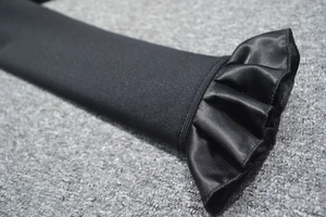 Detail of black long sleeve cuff featuring elegant satin ruffle trim and matte fabric