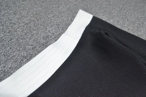 Vue détaillée du tissu en sergé noir et de la ceinture élastique blanche de la robe