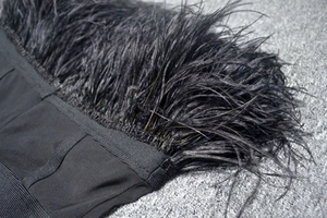 Close-up of black ostrich feathers and ribbed bandage fabric on an elegant party dress