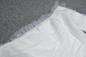 Detailed close-up of white bandage dress with pleated mesh lace and invisible zipper