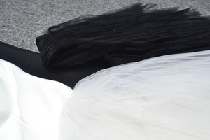 Detailed close-up showing the contrast between black pleated tulle and white textile textures