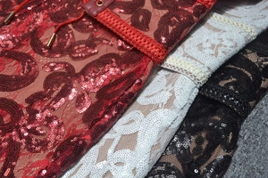 Close-up of lace fabric with sequins and braided trim in red, white and black colors