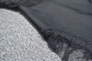 Detail of elegant black bandage dress featuring floral eyelash lace trim and refined stitching