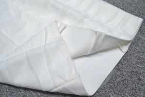 Detailed view of layered white pleated mesh fabric and elastic ribbed bandage dress texture