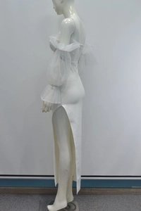 Détail de robe de soirée blanche à épaules dénudées avec manches en tulle et fente haute