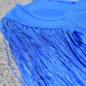 Close-up of bright blue long tassels and dense knit texture on the slim bandage dress