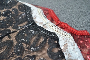 Detail of lace sequins and invisible zippers on black, white, and red jumpsuits