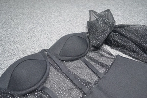 Détail du haut corset en maille noire avec paillettes argentées et bonnets rembourrés