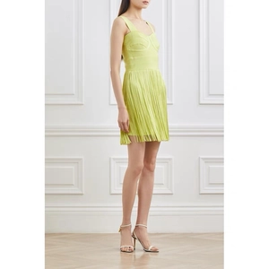 Detailed close-up of lime green bandage dress with structured bustier and long tassels