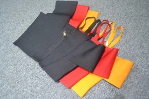 Detail of bandage waist cinchers with metallic zippers and straps in black, red, and orange