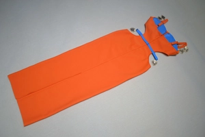 Detail of orange dress featuring blue straps and heart-shaped metal charms with engravings