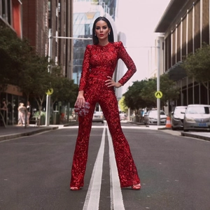 Elegant red lace sequin jumpsuit with long sleeves and flared trousers in street setting