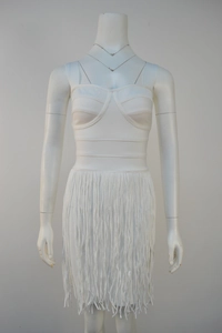 Detail view of white bandage mini dress featuring fringed hem and ribbed bodice structure