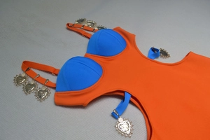 Detail of blue and orange contrast dress with golden heart-shaped metal charms