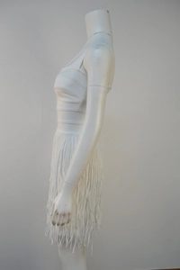 Side profile of a white sleeveless bandage dress featuring tiered fringe detailing