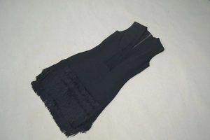 Detailansicht des schwarzen V-Ausschnitt-Bandagenkleids mit Fransensaum und Strickstruktur