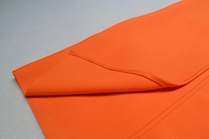 Close-up of bright orange bandage dress showing high-quality knit texture and overlock seams