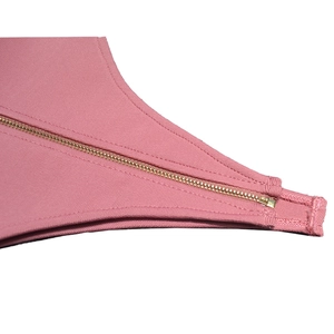 Dettaglio di un tessuto fasciante rosa con cerniera in metallo dorato e cuciture precise