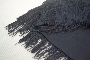 Detailansicht des schwarzen Bandage-Stoffes mit eleganten Fransen und glatten Quasten