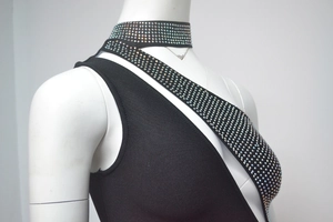 Detail of a black bandage dress featuring sparkling rhinestone straps and high-neck cut
