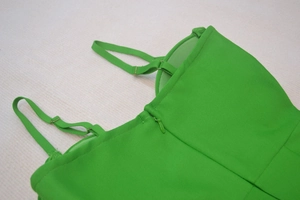 Dettaglio dell'abito fasciante verde con cerniera invisibile e fibbie dorate regolabili