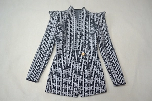 Detail of black and white maze pattern jacquard blazer with embossed gold button