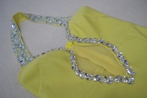 Détail d'une robe bandage jaune dos nu avec col en strass et découpe à la poitrine