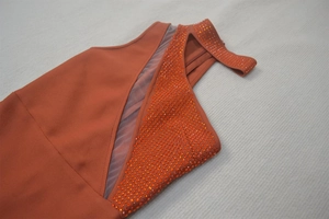 Detail of brick red knit dress with sheer mesh panel and matching crystal rhinestones