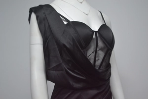 Close-up of a black asymmetric corset dress with mesh panels and satin pleats