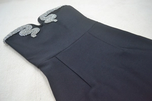 Detailed view of black strapless evening dress featuring V-cut neckline and silver rhinestone trim