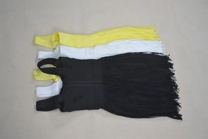Flat lay of mini bandage dresses in black white and yellow with long fringe tassels