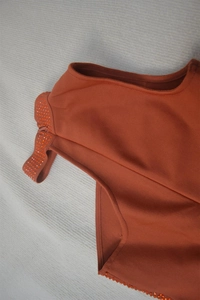 Detail of orange ribbed knit dress with sparkling rhinestone trim on the shoulder strap