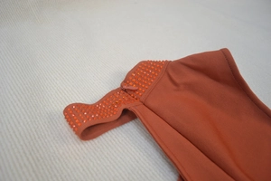 Detail of dark orange bandage dress with matching rhinestones and invisible zipper