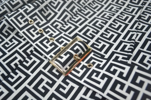 Detail of black and white jacquard fabric with golden metal buckle and eyelets