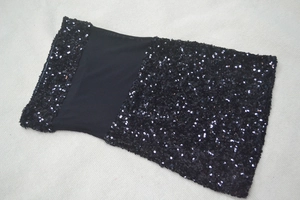 Dettaglio del corpino con paillettes nere e cuciture in rete sull'abito mini donna